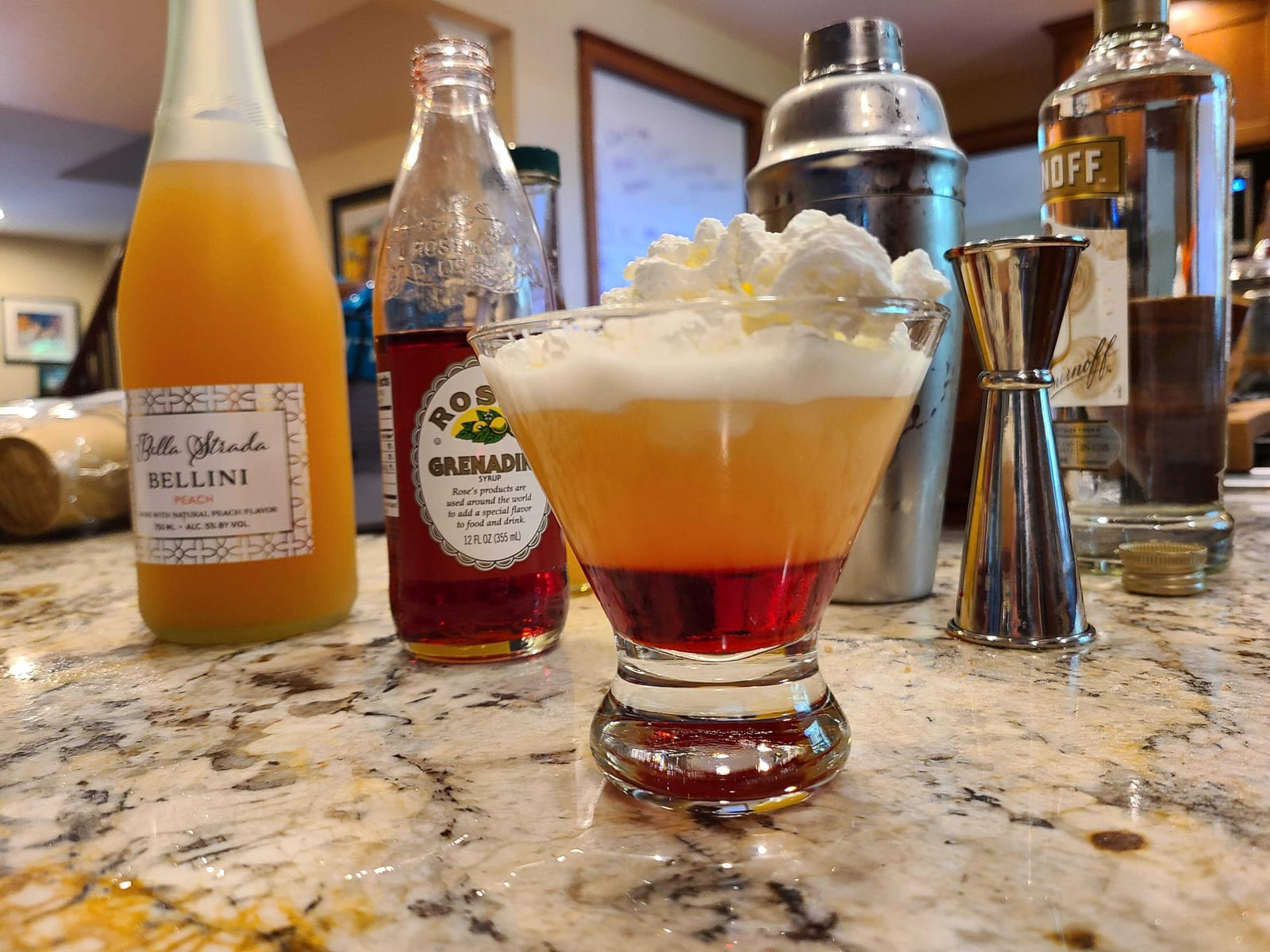 A Candy Corn cocktail layered orange and white, topped with whipped cream and candy corn